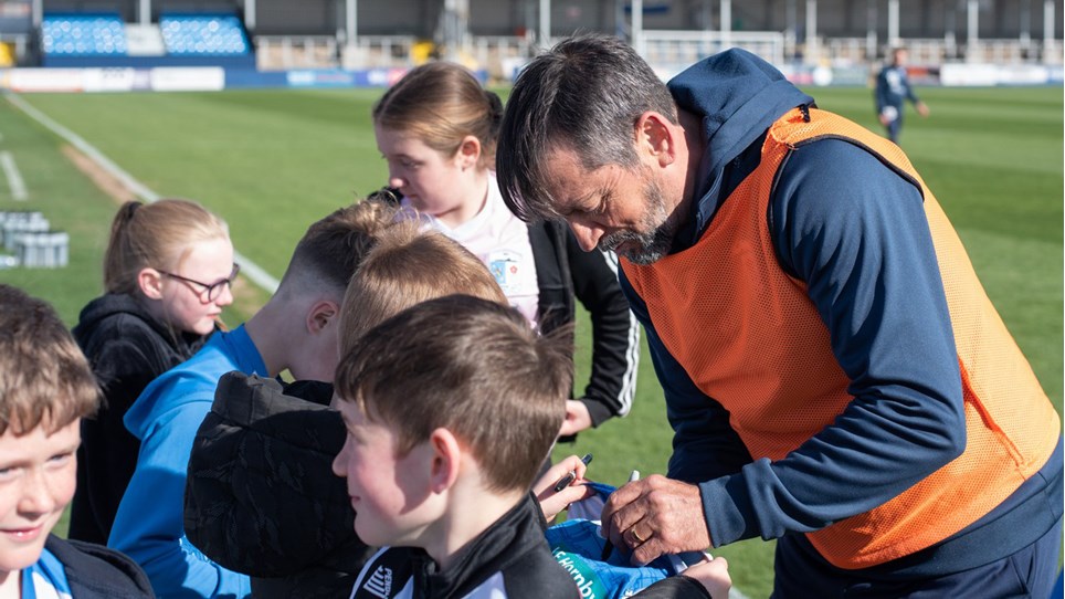 A photograph of Barrow boss Phil Brown signing autographs for supporters