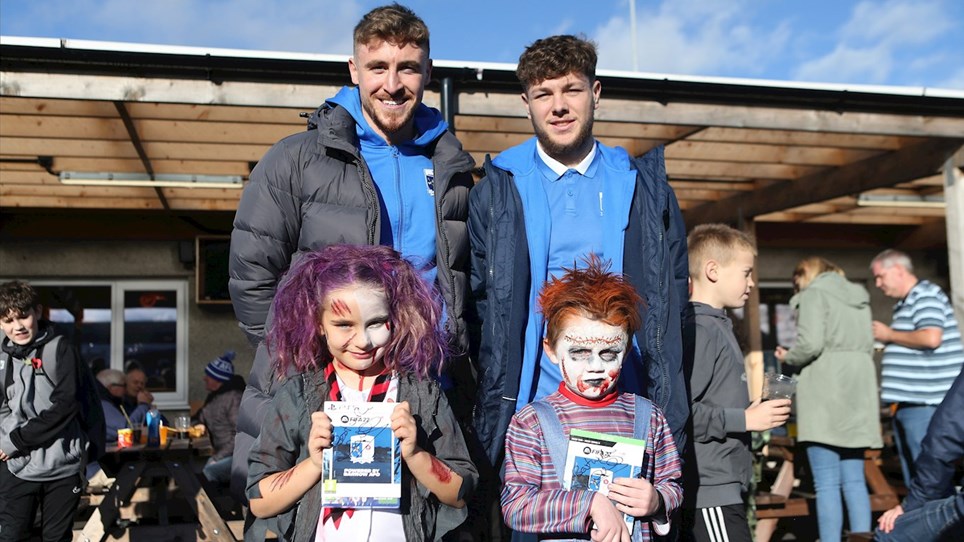 A photograph of Barrow players Tom Beadling and Jordan Stevens with two winners from the Halloween fancy dress competition