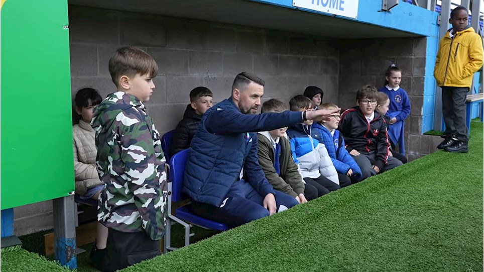 A photograph of Craig Rutherford with local youngsters in the dugouts at Barrow AFC