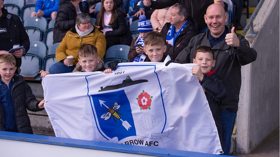 A photograph of Barrow fans holding a flag at the game at Rochdale