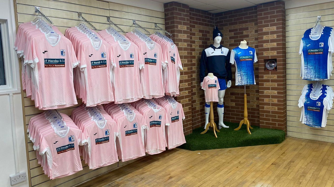 A photograph of the Barrow Club Shop with new home and away shirts in stock