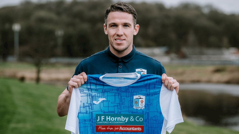 A photograph of Barrow new signing John Rooney holding the Club