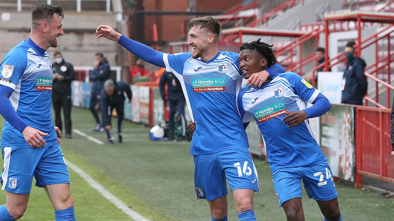 A photograph of Tom Beadling celebrating his goal for Barrow at Exeter City with Scott Quigley and Kgosi Ntlhe