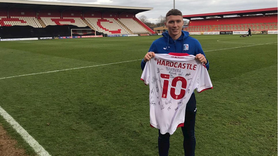 A photograph of Lewis Hardcastle holding the signed Stevenage shirt