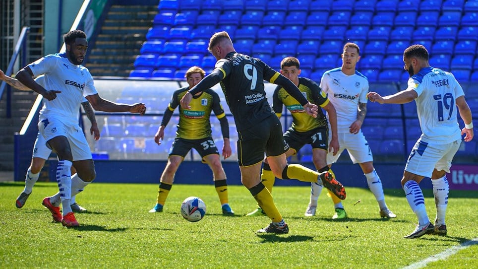 A photograph of Scott Quigley shooting on goal for Barrow during the game at Tranmere Rovers